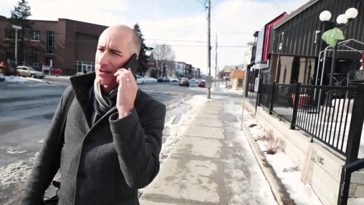 Martin Robitaille au téléphone sur un trottoir enneigé